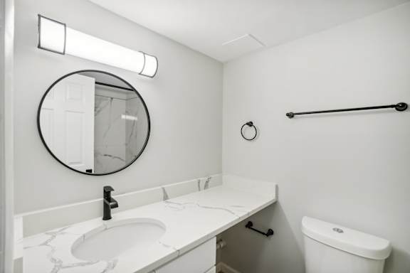A bathroom with a white sink and toilet.