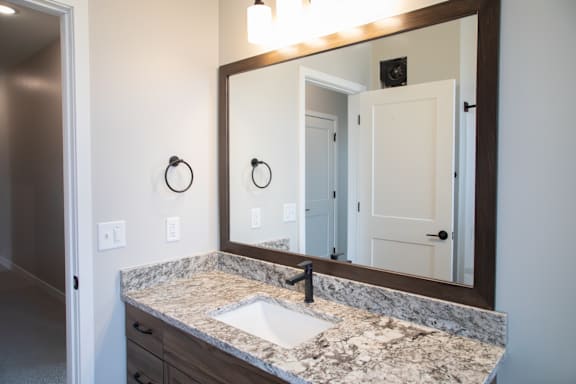 A bathroom with a sink, mirror, and light switches.