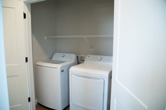 Two white front loading washing machines in a small laundry room.