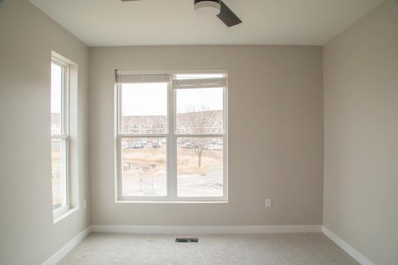A room with a window and a fan on the ceiling.