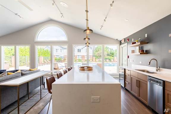 A modern kitchen with a large island and a dining table with chairs.