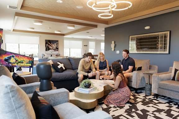 A group of people are sitting around a table in a modern living room.