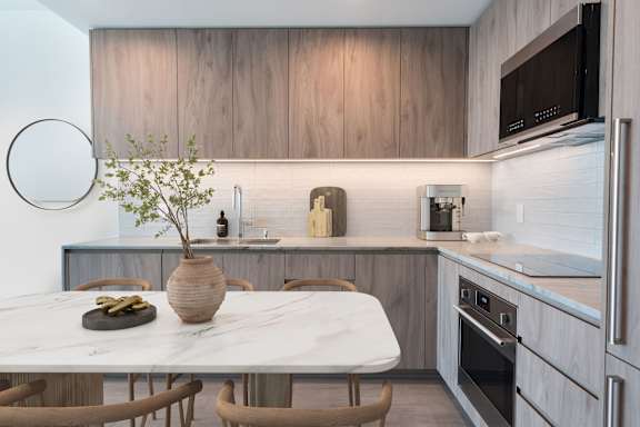 A kitchen with a marble table and wooden chairs.