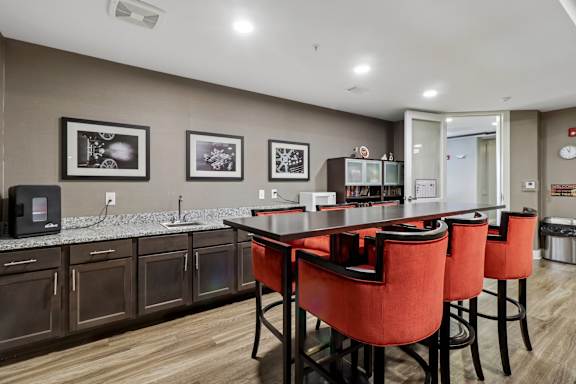 A kitchen with a table and chairs in the foreground and a fridge in the background.