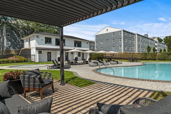 a swimming pool with chairs and umbrellas in front of a building at Chestnut Hill Village, Philadelphia, PA