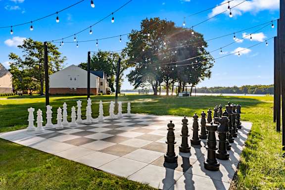 A giant chess board with black and white pieces in a grassy area.