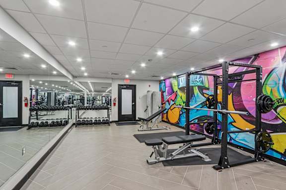 A gym with a row of treadmills and a row of weight machines.
