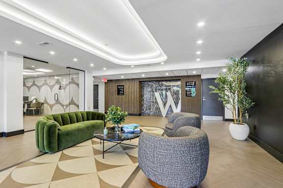 A modern waiting area with a green sofa, grey armchair, and a coffee table.