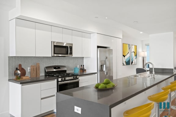 a kitchen with white cabinets and a counter top with a bowl of fruit
