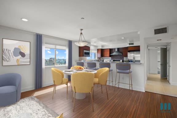 a dining area with a table and chairs and a kitchen in the background