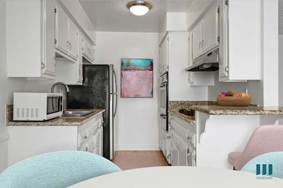 a white kitchen with stainless steel appliances and a blue rug