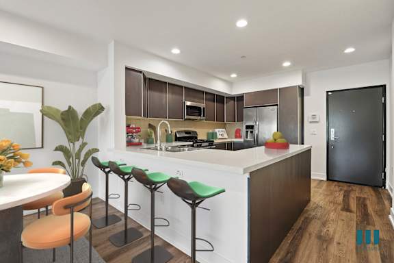 A modern kitchen with a bar stool and a plant.