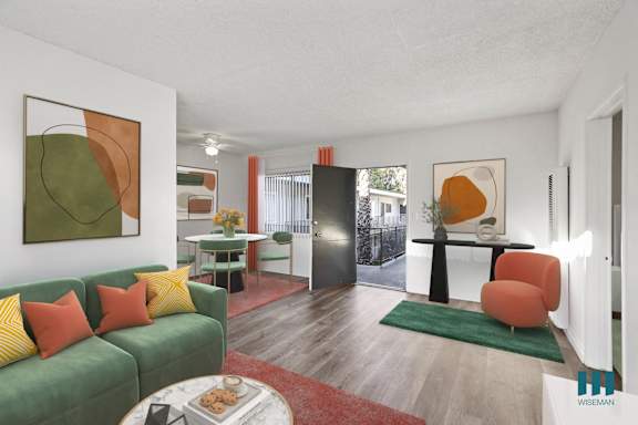 A living room with a green couch and a painting on the wall.