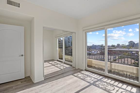 Bedroom with Mirrored Closet, Private Balcony, and Vinyl Flooring