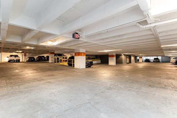 A parking garage with a sign that says "EXIT" on the ceiling.