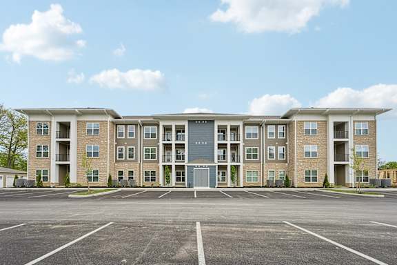 A large apartment complex with a parking lot in front.