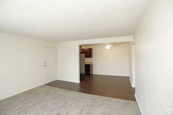 View of front door from carpeted living room and wood panel dining area
