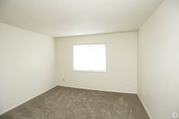 large carpeted bedroom with white walls and fresh grey carpet