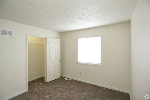Large carpeted bedroom with large closet and window with blinds and vent