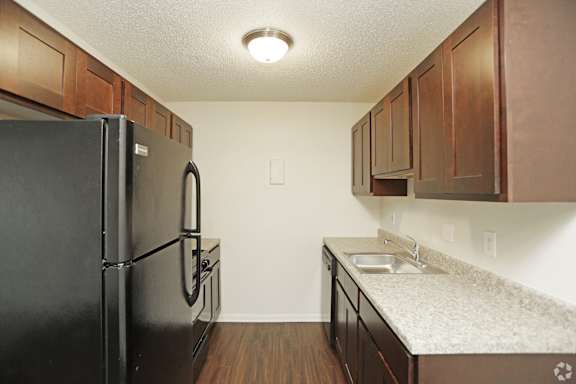 Updated kitchen with black appliances and dark wood cabinets and light grey countertop