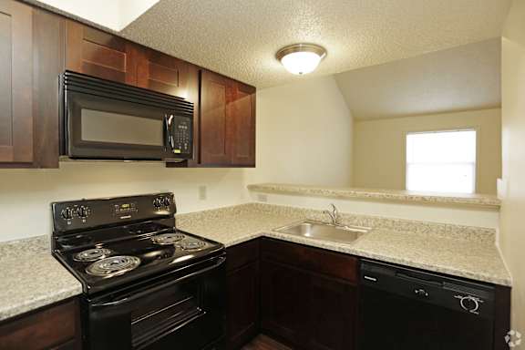 Kitchen with black appliances including microwave and wrap around light grey countertops