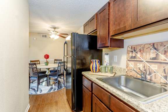 Spacious modern kitchen with black appliances, decorative pottery on light grey countertops and large on basin sink