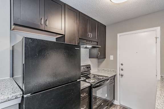 Kitchen with dark cabinets and granite-style countertops at Chapel Creek Apartments Dallas