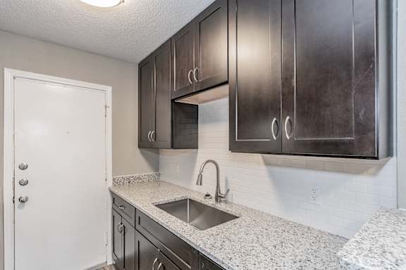 Kitchen with dark cabinets and granite-style countertops at Chapel Creek Apartments Dallas