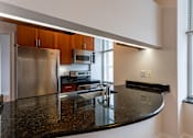 Thumbnail 17 of 23 - A kitchen with a granite counter top and stainless steel appliances.