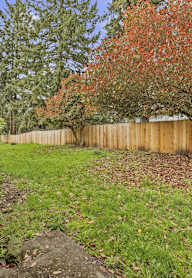 A backyard with a wooden fence and a tree with red leaves.