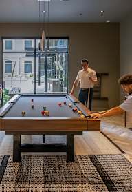 Two men playing pool in a room with a pool table.