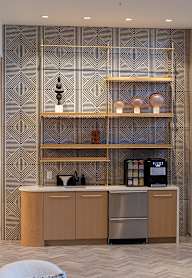 A modern kitchen with a patterned wallpaper and a wooden cabinet.