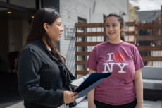 a woman holding a clipboard and talking to a young girl