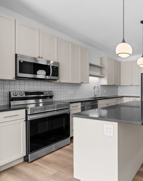 a renovated kitchen with white cabinets and black counter tops at The Mera, St Louis Park, MN 55426