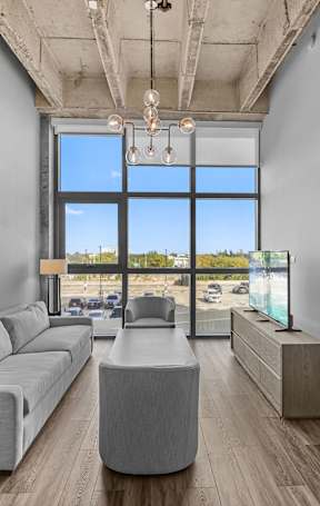 A modern living room with a large window overlooking a parking lot.