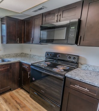 a kitchen with dark wood cabinets and granite counter tops and a stove and microwave
