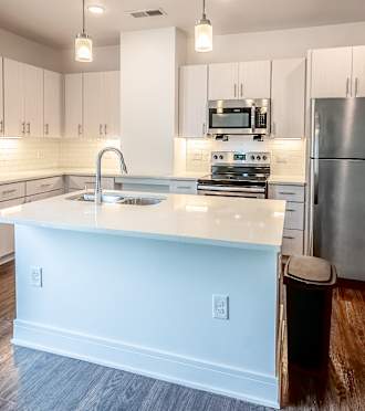 an empty kitchen with a large island and stainless steel appliances