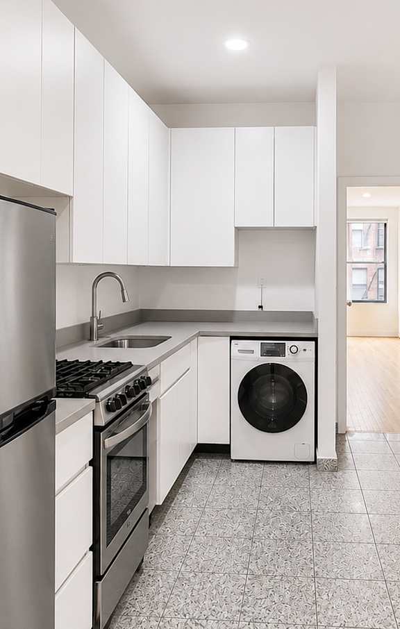 A kitchen with a black counter top and wooden floors.