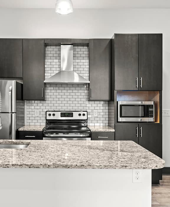A modern kitchen with a granite countertop and stainless steel appliances.