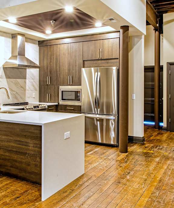 A kitchen with a white counter top and wooden floors.