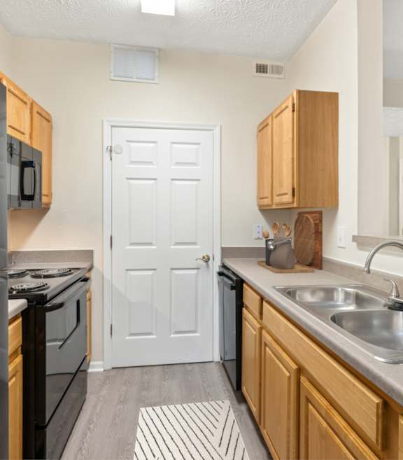 A kitchen with a black refrigerator and wooden cabinets.