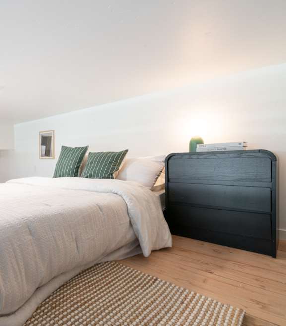 A bedroom with a bed and a nightstand.
