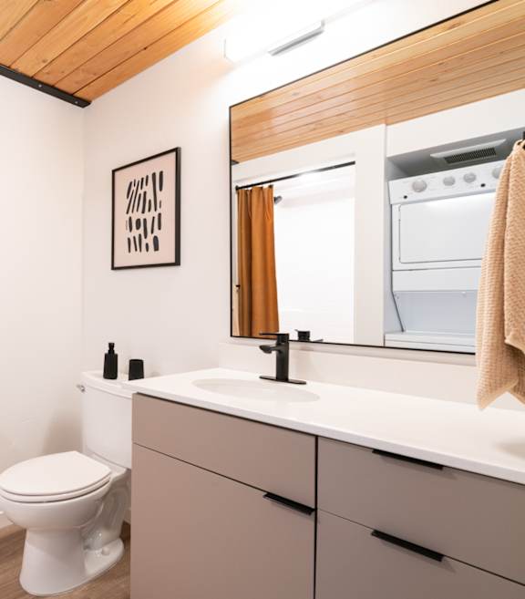 A white toilet sits in a bathroom with a wooden ceiling.