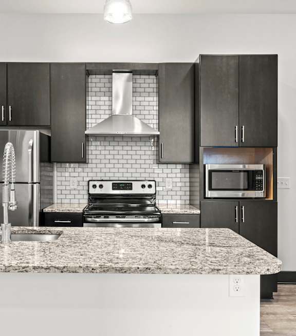 A modern kitchen with a granite countertop and stainless steel appliances.