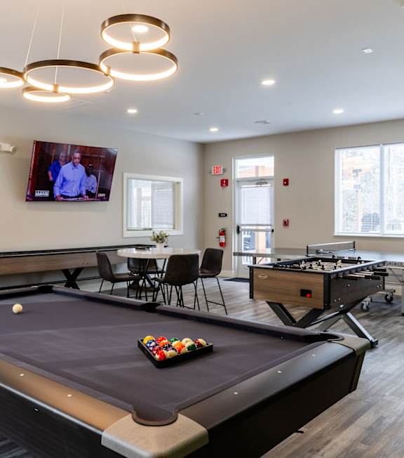 A pool table in a room with a television mounted on the wall.