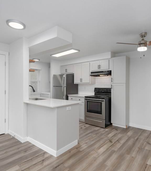 A kitchen with white cabinets and a wooden floor.