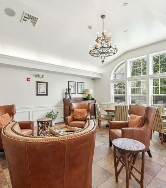 A living room with a large brown leather sofa and a chandelier.