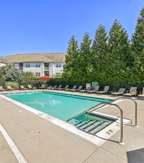 A swimming pool surrounded by lounge chairs and trees.