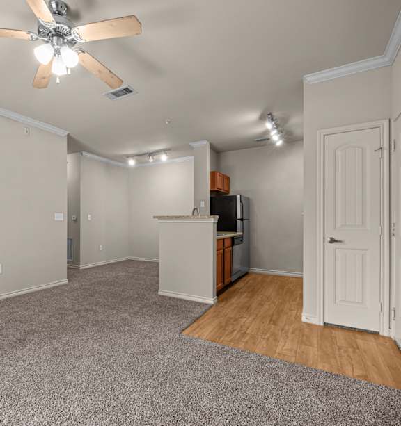 A room with a ceiling fan and a kitchenette.