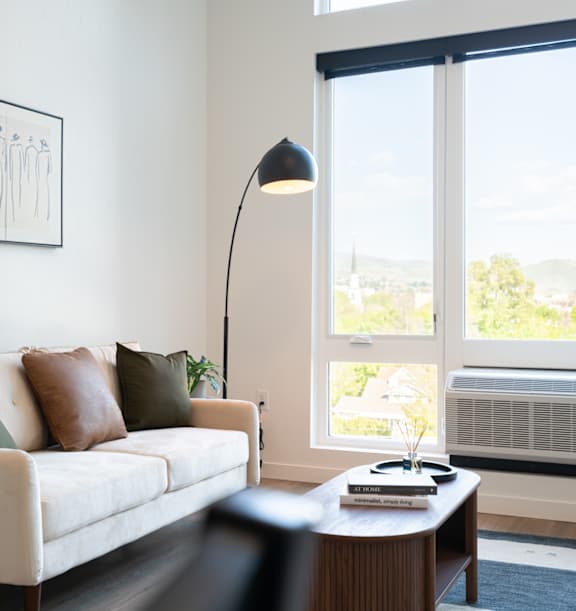 A living room with a couch, a table, a lamp, and a picture on the wall.